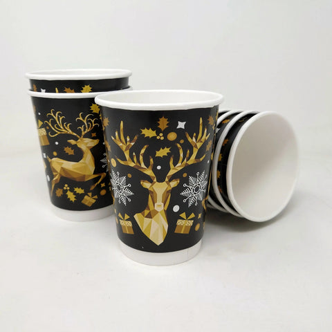 Paper cups with gold deer and snowflake design on a white background